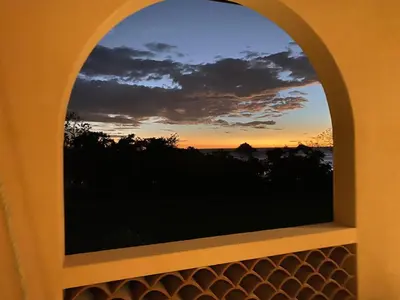 an arched window with a sunset in the background at Plaza Mercado 20 At Las Catalinas in Playa Danta
