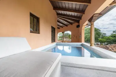 a bedroom with a bed and a swimming pool at Plaza Mercado 20 At Las Catalinas in Playa Danta