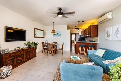 a living room with a blue couch and a kitchen at Punta Plata 523- Ocean View Condo in Playa Flamingo