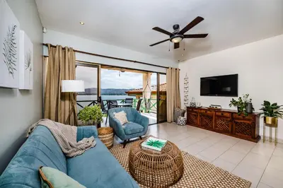 a living room with a blue couch and a tv at Punta Plata 523- Ocean View Condo in Playa Flamingo