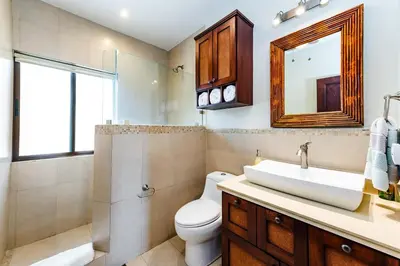 a bathroom with a sink and a toilet and a mirror at Punta Plata 523- Ocean View Condo in Playa Flamingo