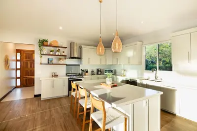 a kitchen with white cabinets and a large island with chairs at Casa Natura- 3 Bedroom Ocean View Home At Mar Vista in Brasilito