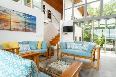 a living room with blue furniture and windows at Casa Brisas Del Mar- Luxury 6 Bedroom Ocean View Home in Puerto Viejo