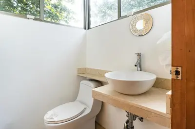 a bathroom with a sink and a toilet and a window at Casa Brisas Del Mar- Luxury 6 Bedroom Ocean View Home in Puerto Viejo