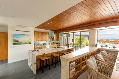an open kitchen with wooden ceilings and a large island at Casa Brisas Del Mar- Luxury 6 Bedroom Ocean View Home in Puerto Viejo