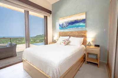 a bedroom with a bed and a large window at Casa Sunset At Mar Vista in Playa Flamingo