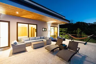 a patio with a couch and chairs and a hammock at Casa Sunset At Mar Vista in Playa Flamingo