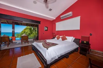 a red bedroom with a bed and a large window at Casa Suenos-Beautiful Beachfront House in Tempate