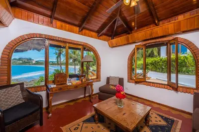 a living room with windows and a table and a desk at Casa De La Playa- Beachfront Home At Flamingo in Playa Flamingo