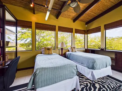 two beds in a room with windows at Villa Carao #3 - A Private 4 Bedroom Resort Villa in Brasilito
