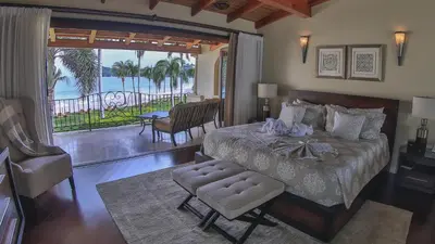 a bedroom with a bed and a view of the ocean at Palms 3- Luxury Beachfront Villa in Playa Flamingo