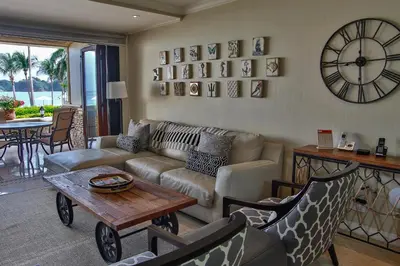 a living room with a couch and a table and a clock at Palms 3- Luxury Beachfront Villa in Playa Flamingo