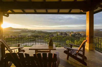 a patio with a table and chairs and the sunset at Malinche 423-B, Ocean View 2 Br Condo At Reserva Conchal in Brasilito