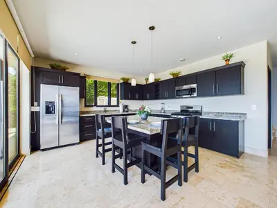a kitchen with black cabinets and a table with chairs at Dos Rios #70- 6 Bedroom Home On 12 Acre in Brasilito