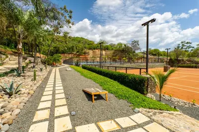 a bench on a gravel path next to a tennis court at Dos Rios #70- 6 Bedroom Home On 12 Acre in Brasilito