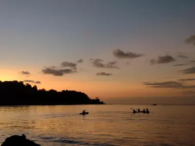 a group of people in boats in the water at sunset at Eco Lodge&Farm Rustic Roots Reserve in Drake
