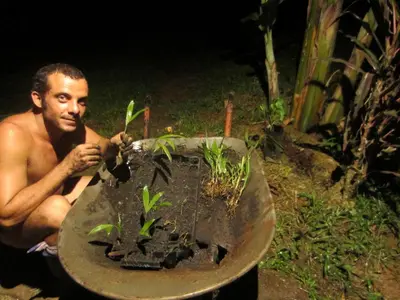 a man sitting next to a planter with a plant at Eco Lodge&Farm Rustic Roots Reserve in Drake