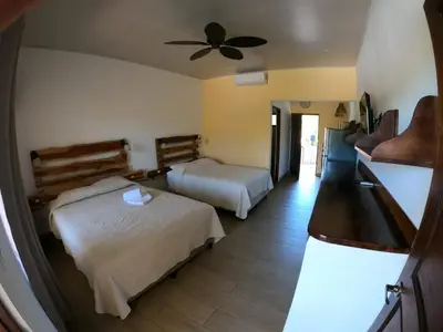 a hotel room with two beds and a ceiling fan at Cabinas El Colibri, Apart Hotel in Carrillo
