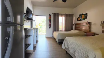 a hotel room with two beds and a television at Cabinas El Colibri, Apart Hotel in Carrillo