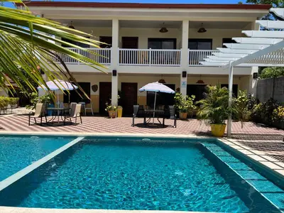a house with a swimming pool in front of a house at Cabinas El Colibri, Apart Hotel in Carrillo