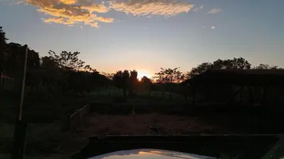a sunset in a field with a car in the foreground at Granja Agua Azul, Wi-FI,AC-WC,Parking,la Fortuna in Fortuna