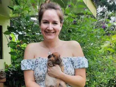 a woman holding a small dog in her arms at Granja Agua Azul, Wi-FI,AC-WC,Parking,la Fortuna in Fortuna