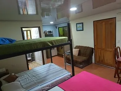 a room with a bunk bed and a couch at Granja Agua Azul, Wi-FI,AC-WC,Parking,la Fortuna in Fortuna