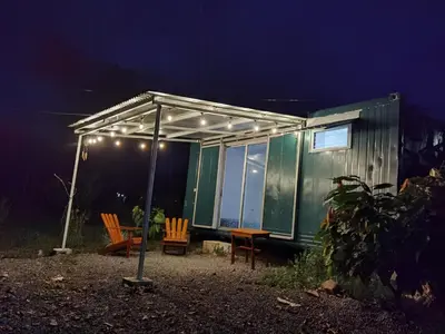 a green tiny house with a tent and chairs at night at The Chocolate Lodge in Jiménez