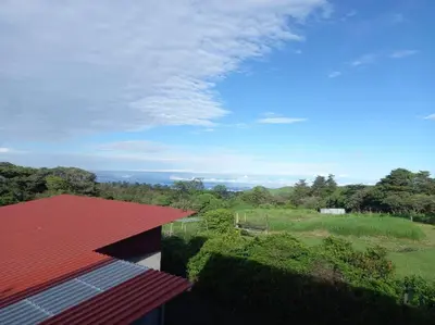 a house with a red roof and a field at Siary Aparment 2 in Monteverde Costa Rica