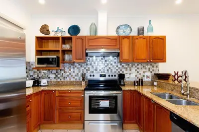 a kitchen with wooden cabinets and a stove top oven at Sunrise 27- 2 Bedroom Ocean View Condo in Tamarindo