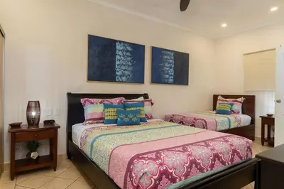 a bedroom with two beds and a table and two pictures at Sunrise 27- 2 Bedroom Ocean View Condo in Tamarindo