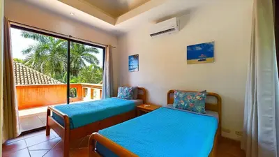 two beds in a room with a large window at Jade Coast #2 in Tamarindo
