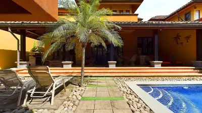 a palm tree and chairs next to a swimming pool at Jade Coast #2 in Tamarindo