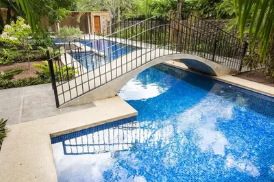 a bridge over a swimming pool with blue water at La Esquina 7 Langosta- 2 Bedroom Luxury Condo in Tamarindo