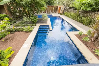 a swimming pool with blue water in a backyard at La Esquina 7 Langosta- 2 Bedroom Luxury Condo in Tamarindo