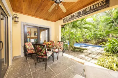 a patio with a table and chairs and a pool at La Esquina 7 Langosta- 2 Bedroom Luxury Condo in Tamarindo