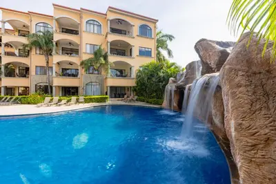 a pool with a waterfall and a hotel at Sunrise 23- 2 Bedroom Ocean View Condo in Tamarindo