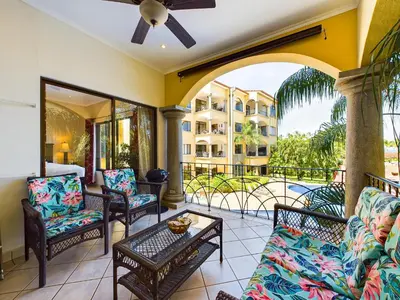 a porch with chairs and a table and a balcony at Sunrise 38- Ocean View 2 Br Condo, Steps To The Beach in Tamarindo