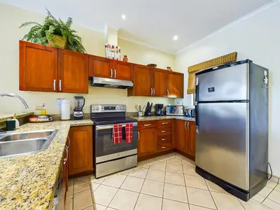 a kitchen with wooden cabinets and a stainless steel refrigerator at Sunrise 38- Ocean View 2 Br Condo, Steps To The Beach in Tamarindo