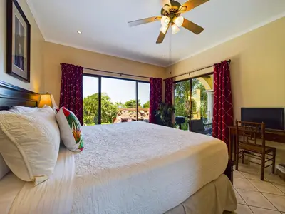 a bedroom with a large bed with a ceiling fan at Sunrise 38- Ocean View 2 Br Condo, Steps To The Beach in Tamarindo