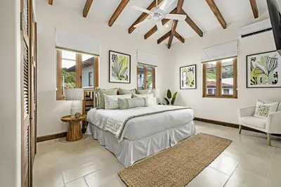 a white bedroom with a bed and a chair at Paseo Miraflores 8 At Las Catalinas in Tempate