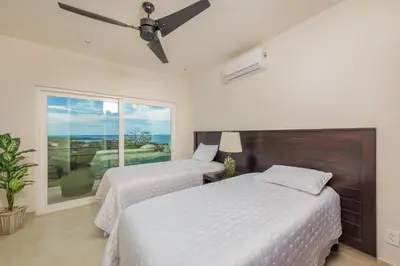 two beds in a bedroom with a window at Casa De La Perla, Ocean View 4 Bedroom Home in Tamarindo