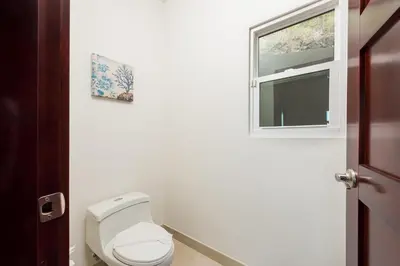 a bathroom with a toilet and a window at Casa De La Perla, Ocean View 4 Bedroom Home in Tamarindo