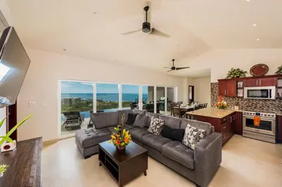 a large living room with a couch and a kitchen at Casa De La Perla, Ocean View 4 Bedroom Home in Tamarindo