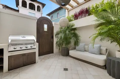 a patio with a grill and a couch and palm trees at Paseo Miraflores 7 At Las Catalinas in Tempate