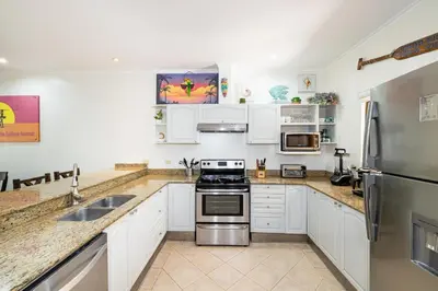 a kitchen with white cabinets and stainless steel appliances at Sunrise 6- Ocean View 2 Br Condo, Steps To The Beach in Tamarindo