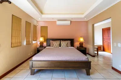 a bedroom with a bed and two lamps on tables at Jade Coast 3- Private 5 Bedroom Villa in Tamarindo