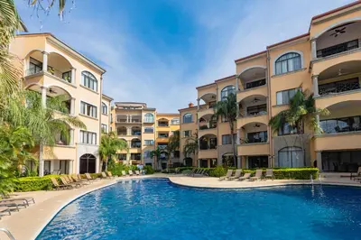 a swimming pool in front of some apartment buildings at Sunrise 1- 3 Bedroom Poolside Condo in Tamarindo