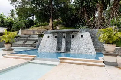 a swimming pool with a stone wall and stairs at Matapalo 101- 3 Bedroom Poolside Luxury Condo At Tamarindo in Tamarindo