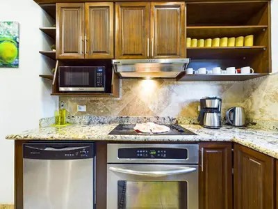 a kitchen with wooden cabinets and a stove top oven at Matapalo 101- 3 Bedroom Poolside Luxury Condo At Tamarindo in Tamarindo